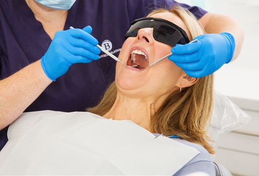 Lady with blonde hair in a dental chair receiving treatment with her mouth wide open